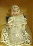 This 1:12 scale baby girl by Heidi Ott is dressed in a long white lace dress. She is soft bodied