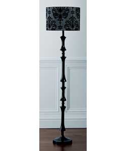 This freestanding, ornately designed floor lamp has a sturdy black metal base, with a sleek black fa