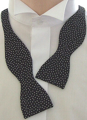 A lovely black self-tie bow tie with white dots all over in a random design.